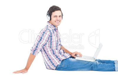 Man with headphones sitting on the floor using laptop