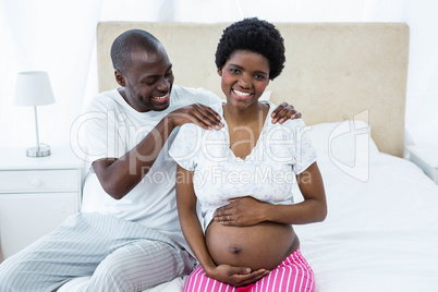 Man massaging pregnant womans shoulder on bed