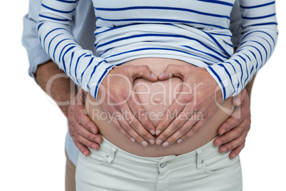 Couple making a heart shape on belly