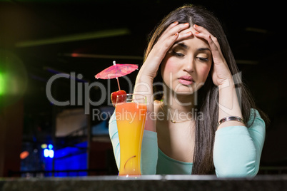 Depressed woman having cocktail drink at bar counter