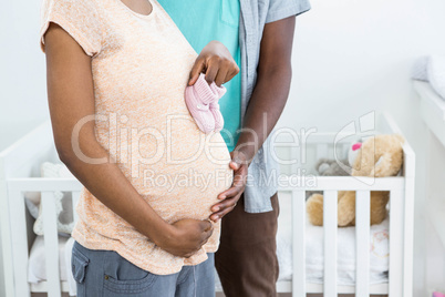Pregnant couple holding pink baby shoes