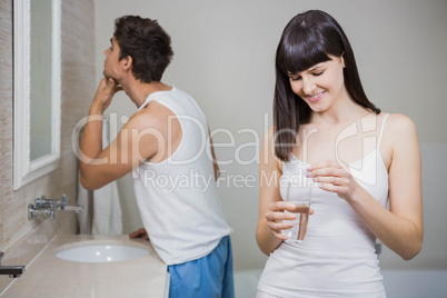 Beautiful woman holding pill and glass of water