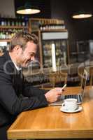 Thoughtful man using laptop and smartphone