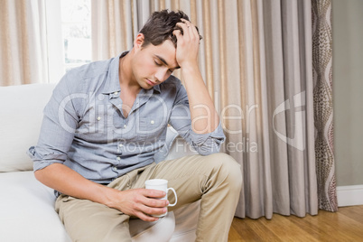 Stressed young man sitting on sofa