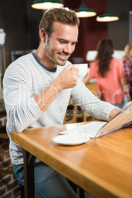 Handsome man reading newspaper and having a coffee