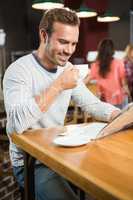 Handsome man reading newspaper and having a coffee