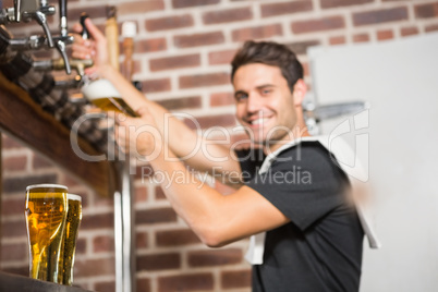 Handsome barman pouring a pint of beer