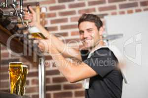 Handsome barman pouring a pint of beer
