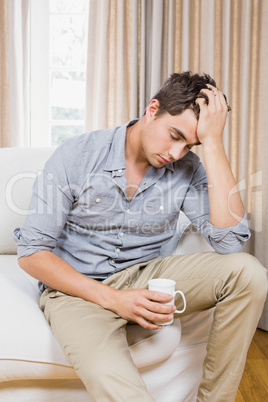 Stressed young man sitting on sofa