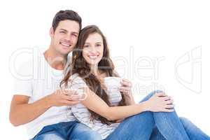 Young couple sitting on floor drinking coffee
