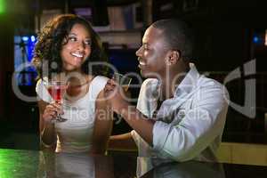 Couple talking and smiling while having drinks at bar counter