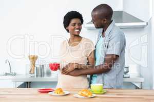 Pregnant couple having breakfast in kitchen
