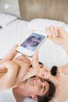 Couple lying on bed and taking a selfie