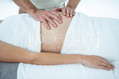 Pregnant woman receiving a stomach massage from masseur