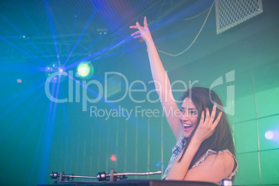 Pretty female DJ waving her hand while playing music