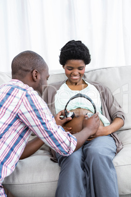 Man holding headphones on pregnant womans stomach