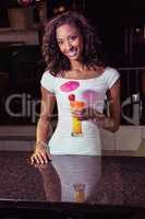 Portrait of young woman having a cocktail at bar counter