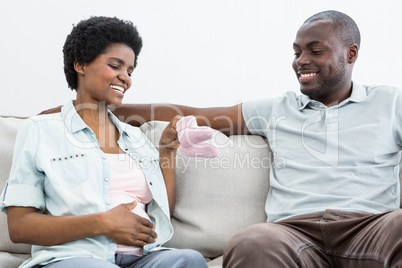 Pregnant couple holding pink baby shoes