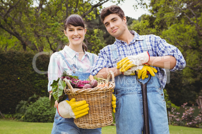 Young couple holding a basket of freshly harvested vegetables