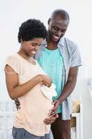 Pregnant couple holding white baby shoes
