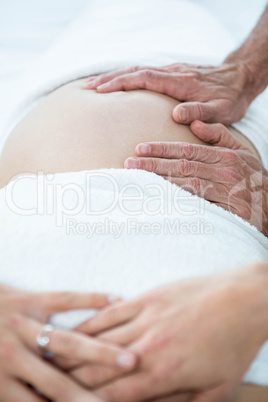 Pregnant woman receiving a stomach massage from masseur