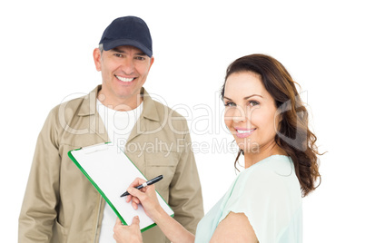 Female customer signing on paper with delivery man