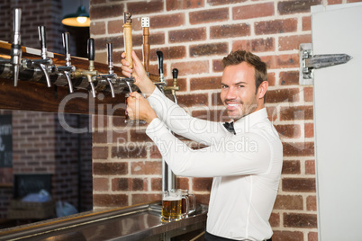 Handsome barman pouring a pint of beer