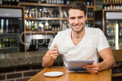 Handsome man using tablet and having coffee