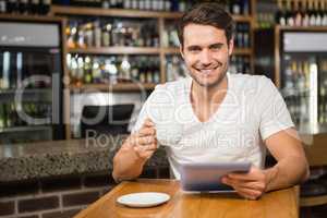 Handsome man using tablet and having coffee