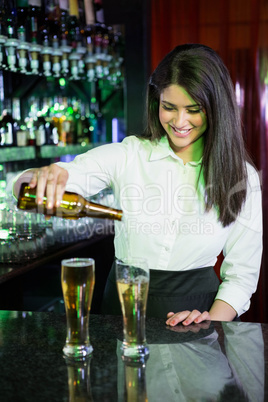 Pretty bartender pouring beer into glasses