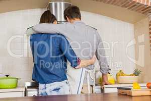 Couple embracing while preparing a meal