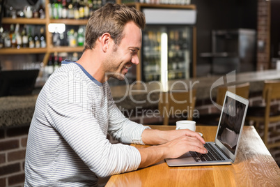 Handsome man using laptop and having coffee