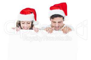 Happy couple with santa hat holding a poster