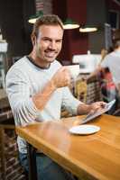 Handsome man using tablet computer and having a coffee