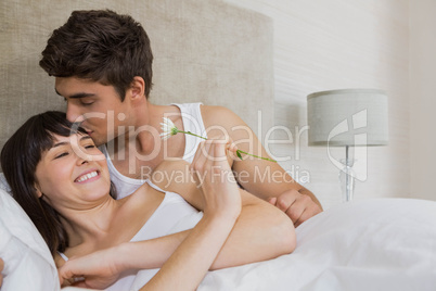 Man kissing woman while offering a flower