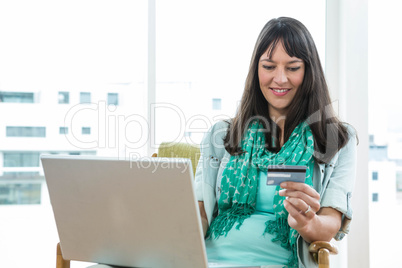 Happy pregnant woman shopping online on her laptop