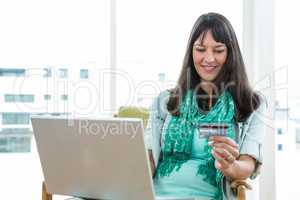 Happy pregnant woman shopping online on her laptop