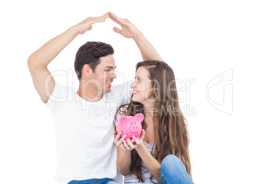 Young couple sitting on floor with piggy bank