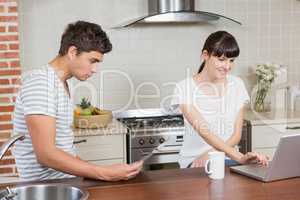 Woman using laptop and man reading newspaper