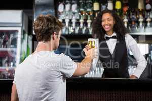 Barmaid serving beer to man