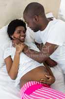 Pregnant couple cuddling on bed