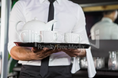 Mid section of waiter serving tea