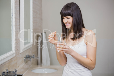 Beautiful woman holding pill and glass of water