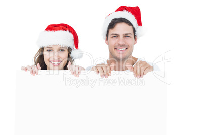 Happy couple with santa hat holding a poster