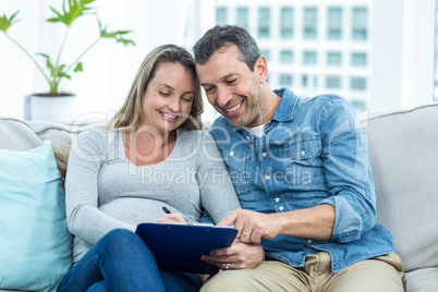 Pregnant woman writing on clipboard