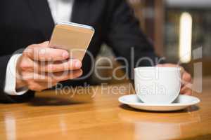 Businessman using smartphone and having coffee