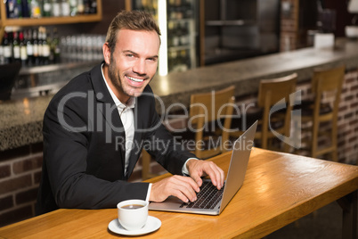 Handsome man using laptop and having a coffee