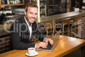 Handsome man using laptop and having a coffee