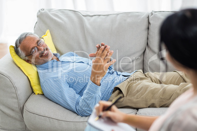 Female doctor writing on notepad while consulting a man