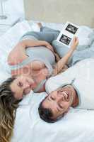 Expecting couple lying on bed